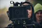 Man using film camera. Another man in green hood in background